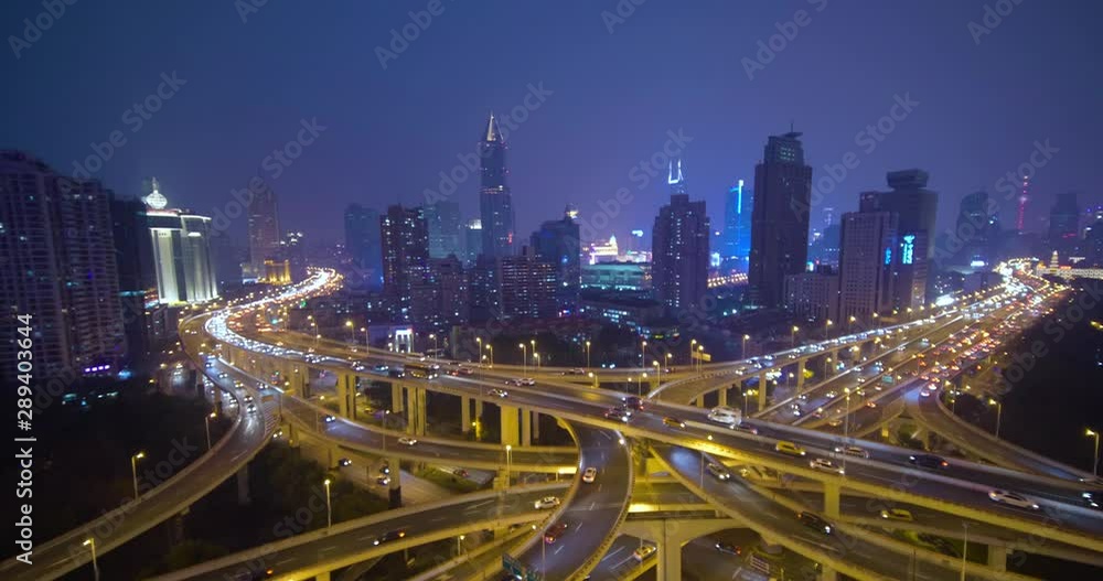 Shanghai city traffic moving in busy intersection junction surrounded by tall modern buildings at night in slow motion, China Shanghai city traffic moving in busy intersection junction surrounded by tall modern buildings at night in slow motion, China