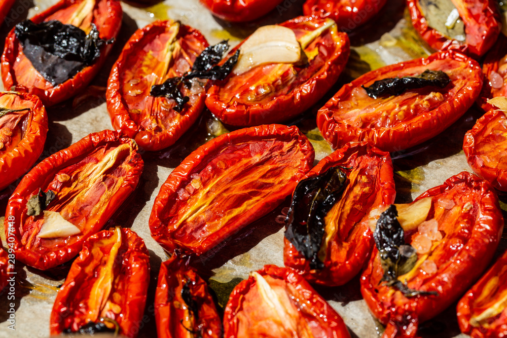 Dried tomatoes with garlic, Basil and salt on parchment paper Dried tomatoes with garlic, Basil and salt on parchment paper