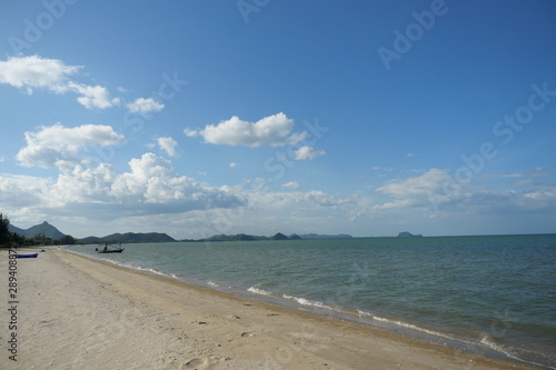 Sea wave splash the brown sand beach with blue sky and white cloud  Fishing boat on the beach with sea and island in background   Khao Sam Roi Yot National Park   Prachuap Khiri Khan   Thailand