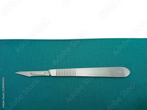 Surgical instrument, scalpel handle number 3 with blade number 11 on surgical green drape fabric isolated on white background  for copy space text.