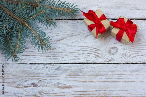 New Year. Gifts with a red bow on a wooden background and a fir branch.