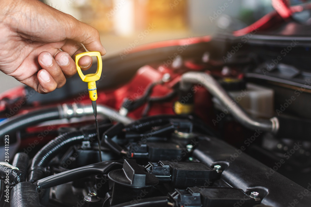 Man service mechanic maintenance inspection service maintenance car Check engine oil level car in garage showroom dealership blurred background. Man service mechanic maintenance inspection service maintenance car Check engine oil level car in garage showroom dealership blurred background.