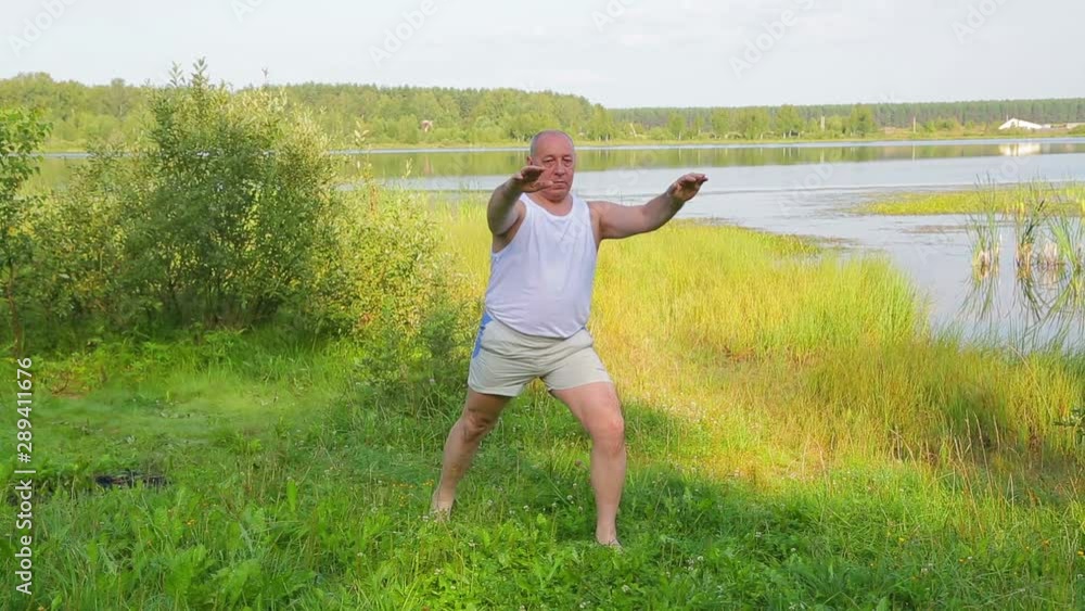 Aged man doing stretching exercises on the lake in the morning Aged man doing stretching exercises on the lake in the morning