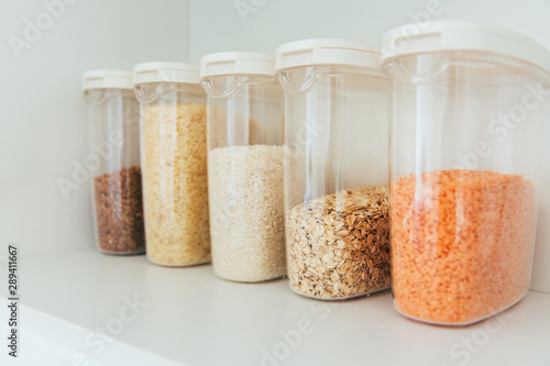 Various seeds in storage jars in pantry, white modern kitchen in background. Smart kitchen organization. Healthy cooking, clean eating concept.