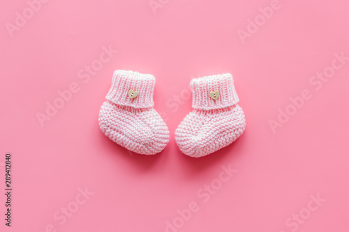Pink knitted footwear for kids on pink background top view space for text