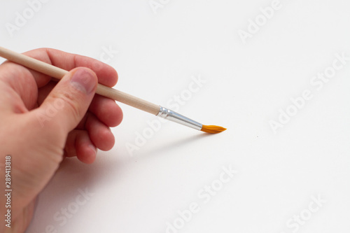 hand with paintbrush on white background
