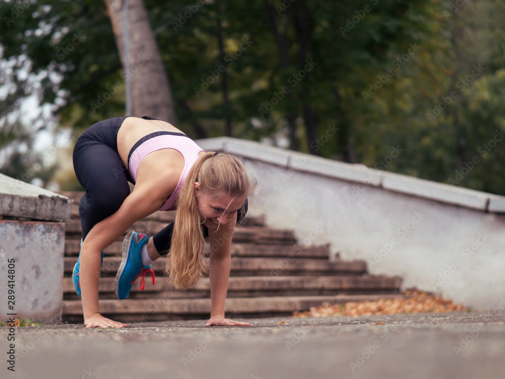 Blond girl doing morning exercise into the park outdoor in summer, bakasana pose, selective focus Blond girl doing morning exercise into the park outdoor in summer, bakasana pose, selective focus