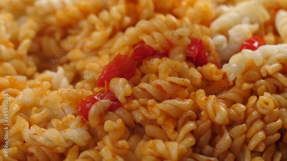 Combining cooked fusilli pasta with tomato sauce made of cherry tomatoes and tomato paste; close up shot Combining cooked fusilli pasta with tomato sauce made of cherry tomatoes and tomato paste; close up shot