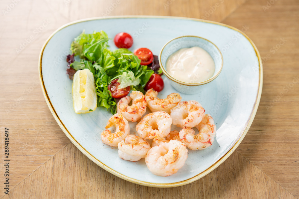 Delicious fresh seafood shrimp with fresh vegetables and lime. Plate on wooden table. Cream sauce Delicious fresh seafood shrimp with fresh vegetables and lime. Plate on wooden table. Cream sauce