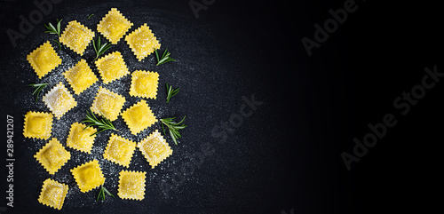 Fototapet Ravioli with flour and herbs on black  background