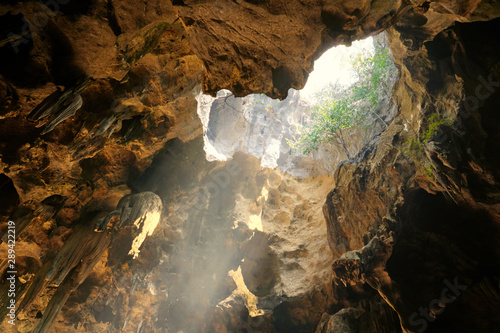 Stalagmite ,stalactite, limestone and tunnel in cave with hole beam sunlight.