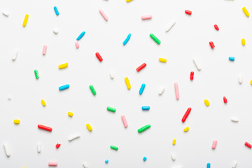 flat lay of colorful sprinkles over white background, festive decoration