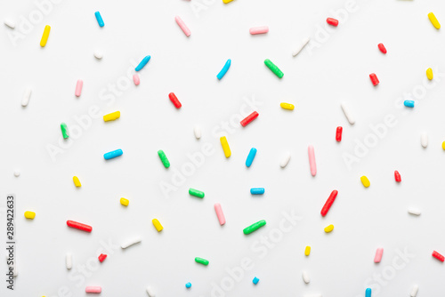 flat lay of colorful sprinkles over white background, festive decoration photo