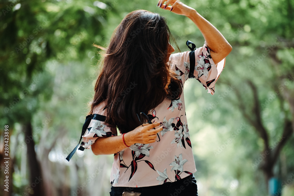 Indian girl standing in park and correcting her hair with hand, at Rajkot, Gujarat, India.