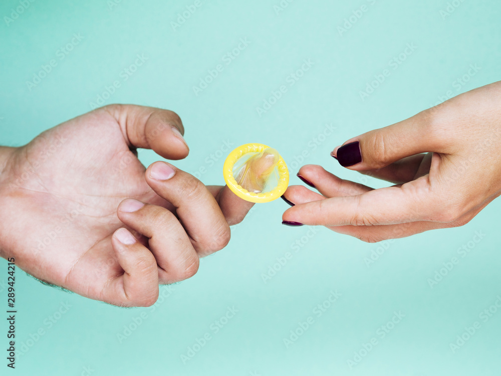 Close-up hands with unwrapped yellow condom