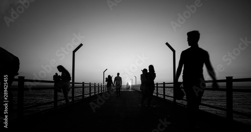 Walking people silhouettes on bridge