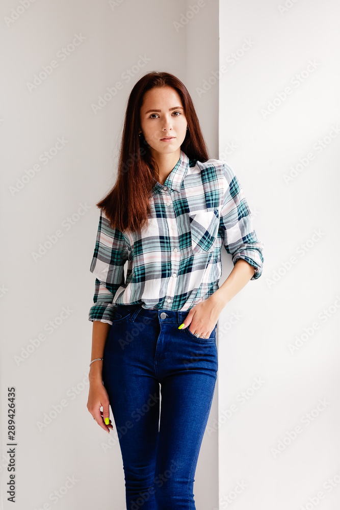 Girl in plaid shirt and jeans is on white background Girl in plaid shirt and jeans is on white background