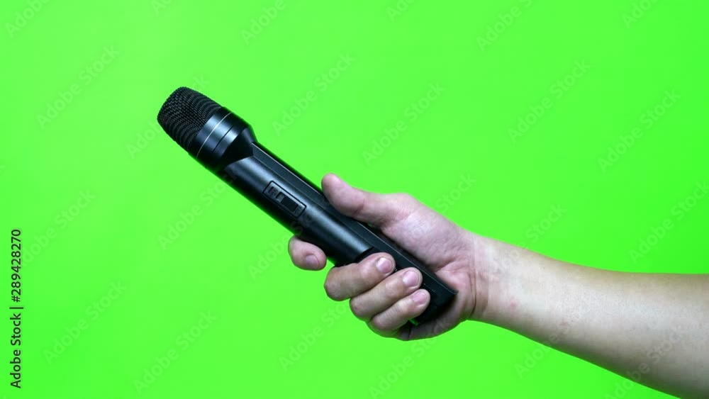 Hand holding black microphone with green screen Hand holding black microphone with green screen