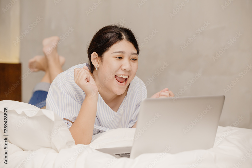 Lazy girl teen happy exciting good news from computer laptop lay on bed working at home Lazy girl teen happy exciting good news from computer laptop lay on bed working at home