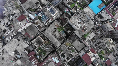 Aerial shot of old break down houses, slum area under clearance, top-down view, camera fly up. Roofs of poor housing units standing close, demolition in progress, abandoned area. photo