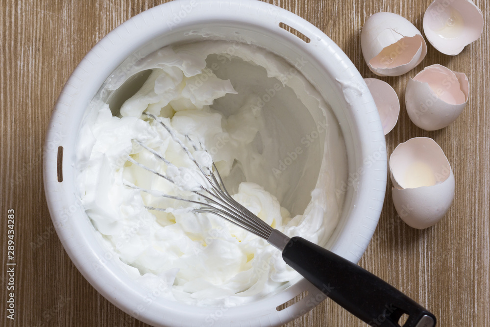 Whisked egg whites in bowl with beater Whisked egg whites in bowl with beater