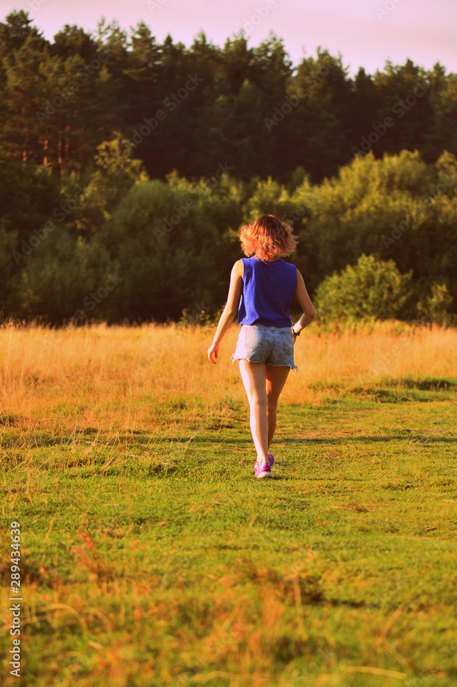 Lovely young girl on a walk in the forest lit by the evening sun. The concept of happiness, youth and beauty of nature Lovely young girl on a walk in the forest lit by the evening sun. The concept of happiness, youth and beauty of nature