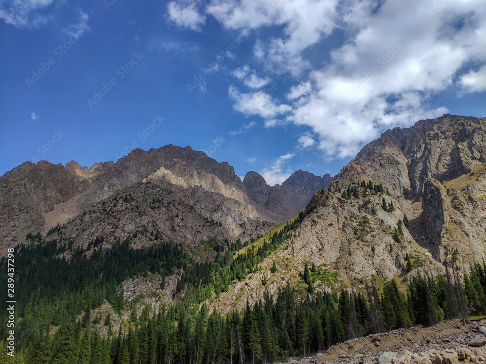 Trans-Ili Alatau mountain range of the Tien Shan system in Kazakhstan near the city of Almaty. Rocky peaks covered with snow and glaciers in the middle of summer under clouds