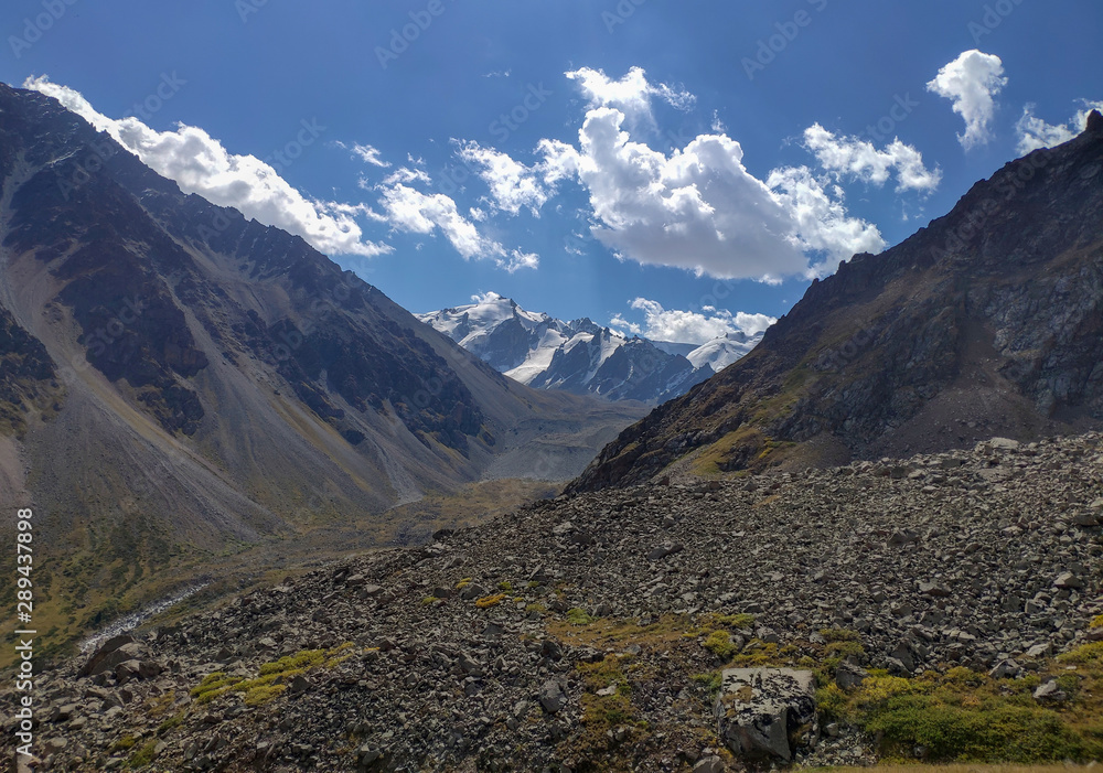 Trans-Ili Alatau mountain range of the Tien Shan system in Kazakhstan near the city of Almaty. Rocky peaks covered with snow and glaciers in the middle of summer under clouds