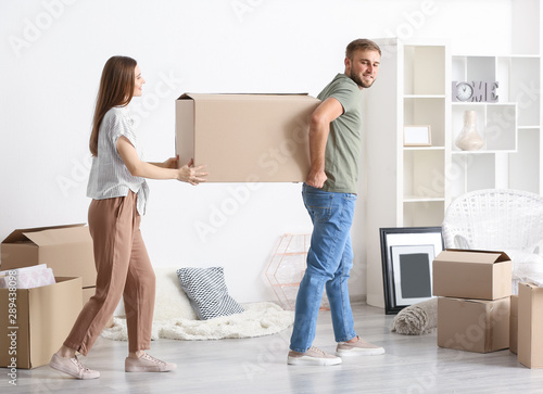 Young couple carrying boxes after moving into new house