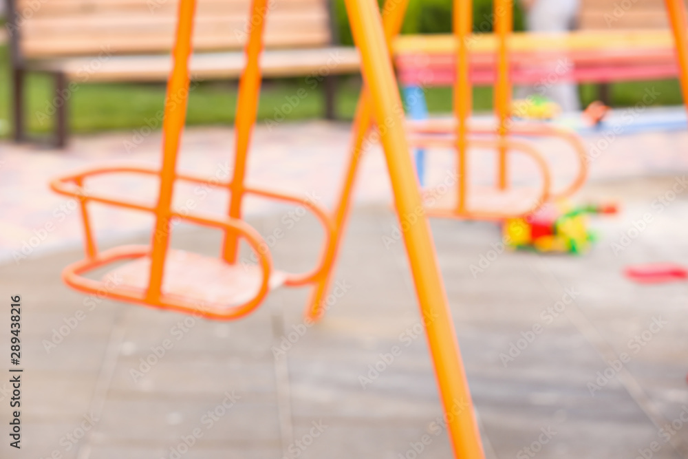 Blurred view of swings on playground in park