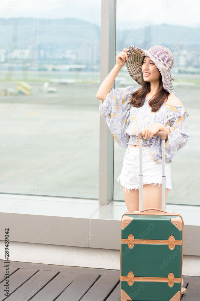 Young asian woman is holding luggage and looking forward to the trip at airport.