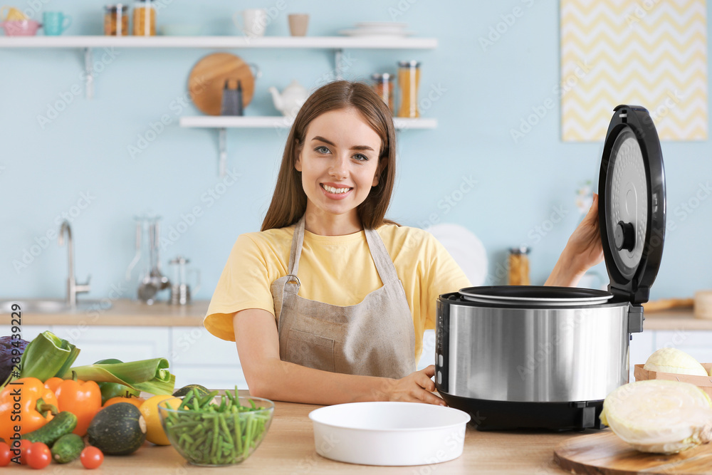 Woman using modern multi cooker in kitchen