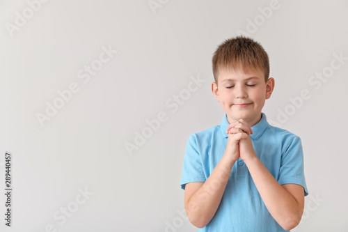 Praying little boy on light...