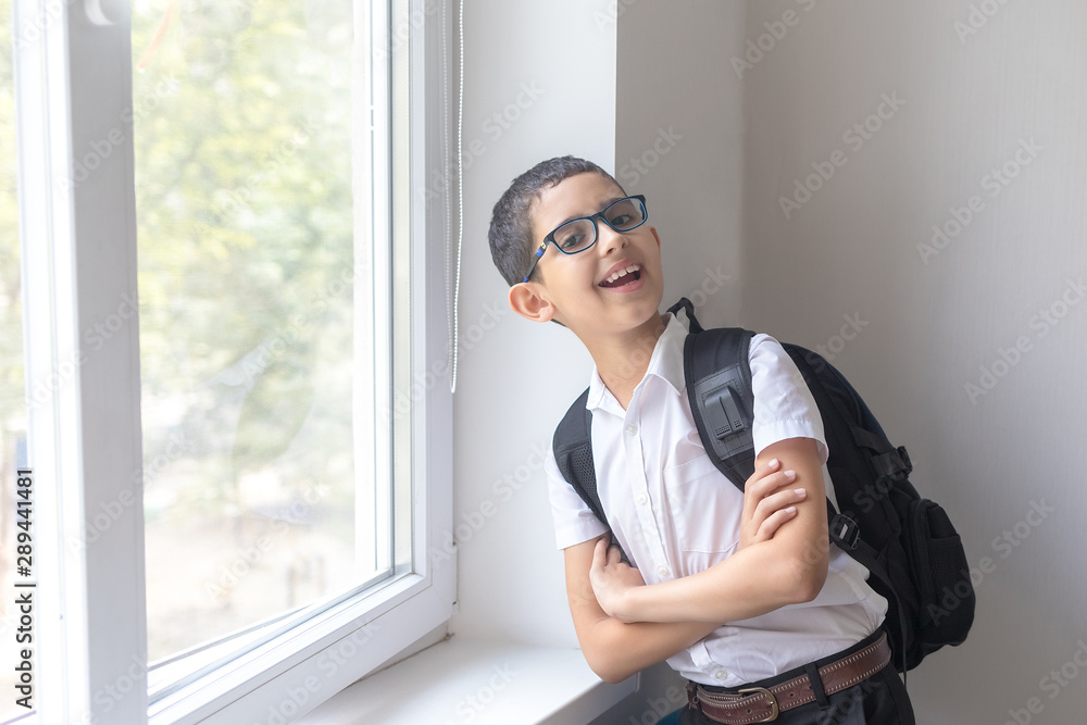 Happy boy in spectacles and shirt near the school window. Isolated over white background. Schoolboy. Teenager. Happy boy in spectacles and shirt near the school window. Isolated over white background. Schoolboy. Teenager.