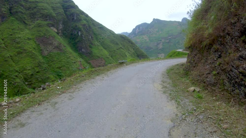 First person view of a narrow winding rough road that cuts through the mountains and valleys of northern Vietnam. First person view of a narrow winding rough road that cuts through the mountains and valleys of northern Vietnam.