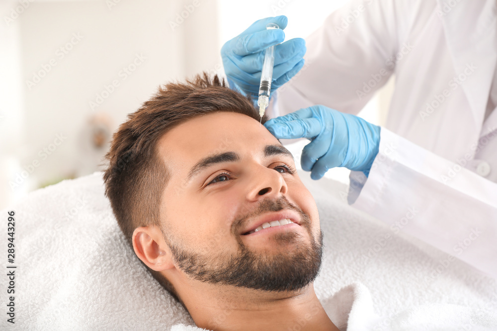 Handsome man receiving filler injection in beauty salon Handsome man receiving filler injection in beauty salon