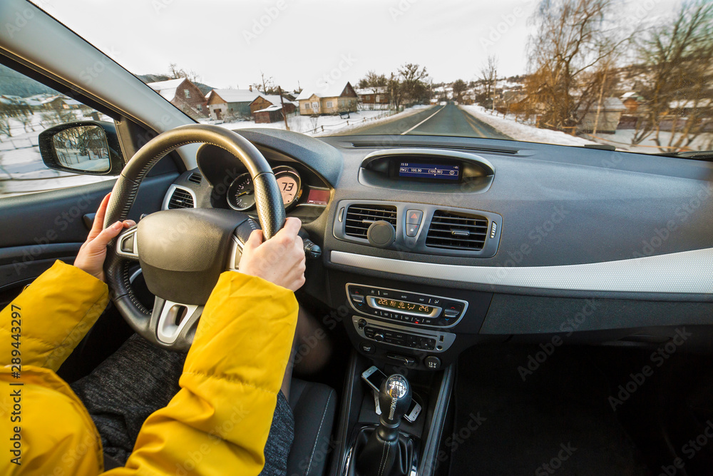 Modern car interior with driver female hands on steering wheel, winter snowy landscape outside. Safe driving concept. Modern car interior with driver female hands on steering wheel, winter snowy landscape outside. Safe driving concept.