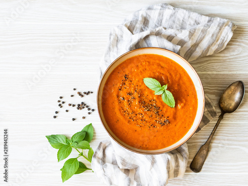 Tomato soup with spices and fresh basil on a white wooden background. Top view. Copy space
