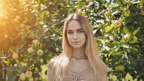 Portrait of a young beautiful seventeen-year-old blonde girl in the apple orchard.