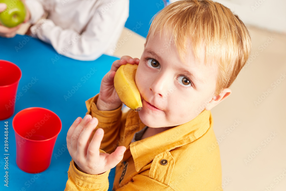 Kleiner Junge spielt mit einer Banane als Snack Kleiner Junge spielt mit einer Banane als Snack