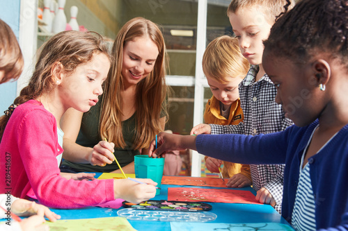 Kinder und Lehrerin malen mit Wasserfarbe
