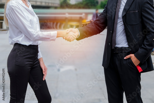 man and woman shaking hands in front of office building