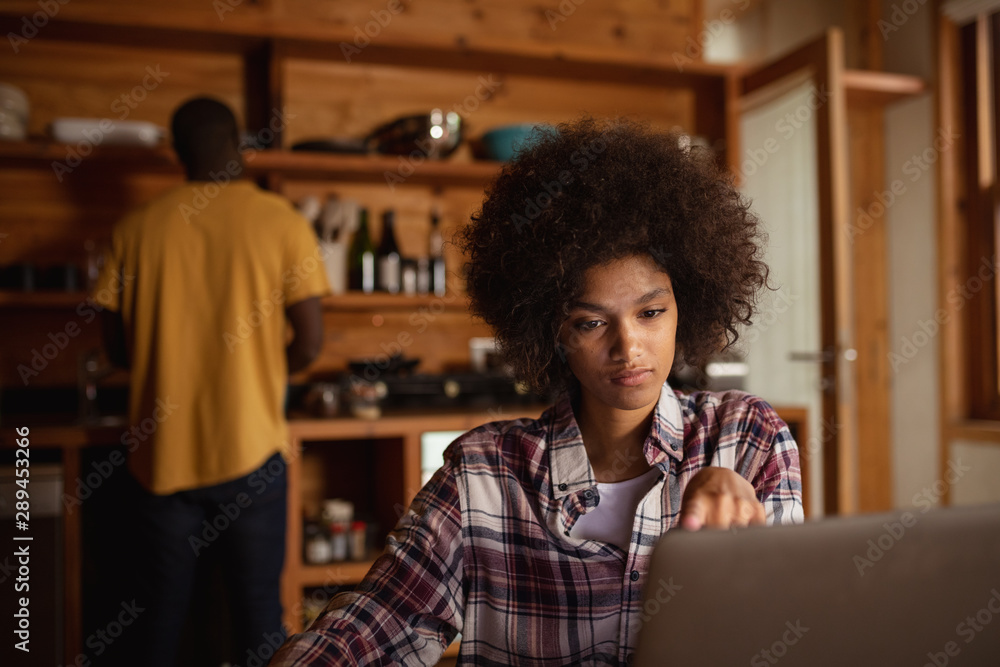 Young woman using laptop in a kitchen Young woman using laptop in a kitchen