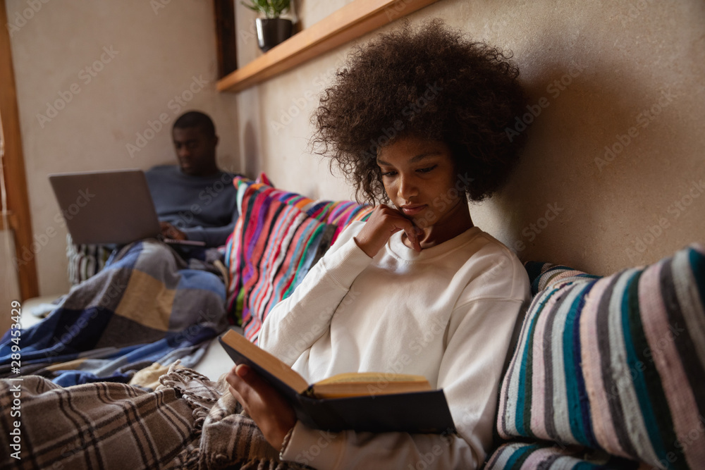 Woman reading on a sofa and man using laptop Woman reading on a sofa and man using laptop