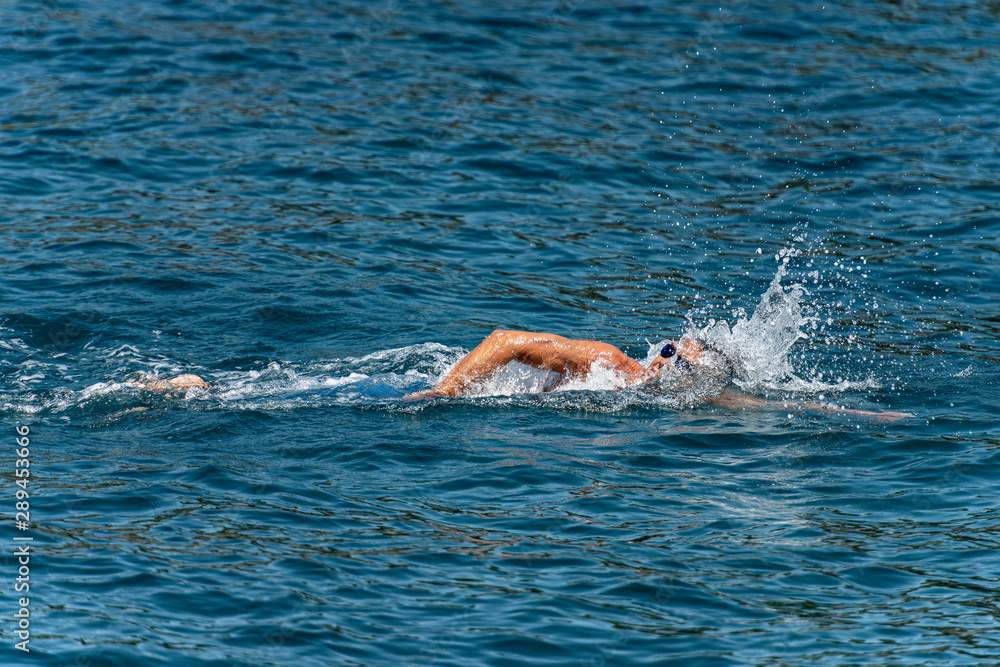 Male freestyle swimmer (Front crawl) in the blue waves of the Mediterranean sea