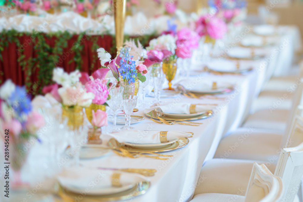 Fototapeta premium Banquet table with forks, knives, plates and flowers and berries