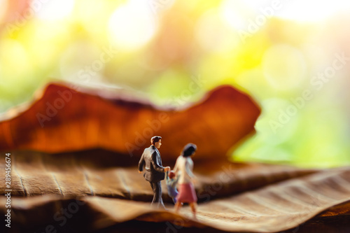 Love and Happy Family. Work Life Balance Concept. Miniature of Father, Mother and Son holding Hands and Walking on Dry Leaf in Park