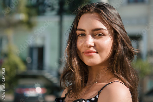 Beautiful young brunette woman dressed in a black dress rests during warm summer traveling in foreign countries.
