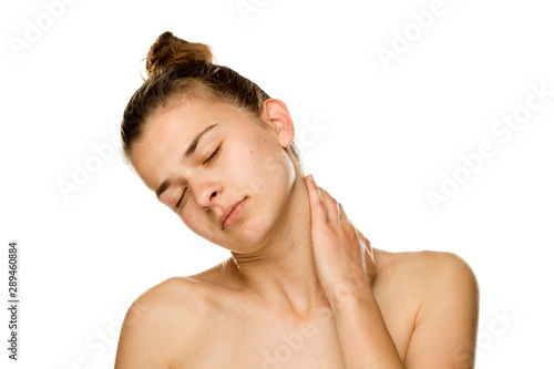 Portrait of young tired woman touches her neck on white background