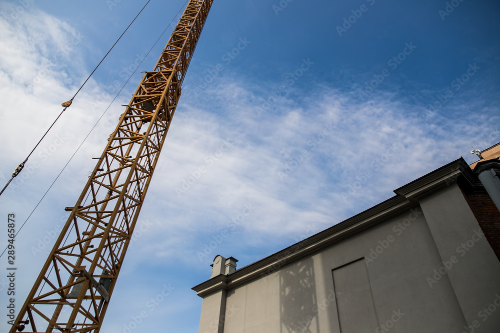 Construction site with cranes on sky background. Big yellow machinery construction crane tool of building industry for heavy lifting on blue sky background. Business engineering equipment modern